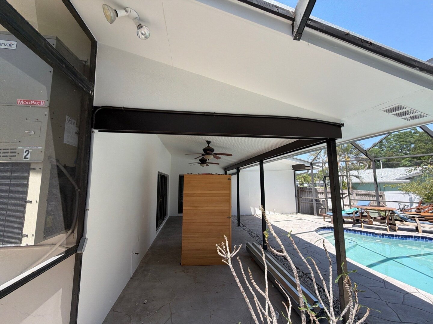 Dunedin home covered pool patio after exterior painting in white with tongue-and-groove wood ceiling refinished by Highmark