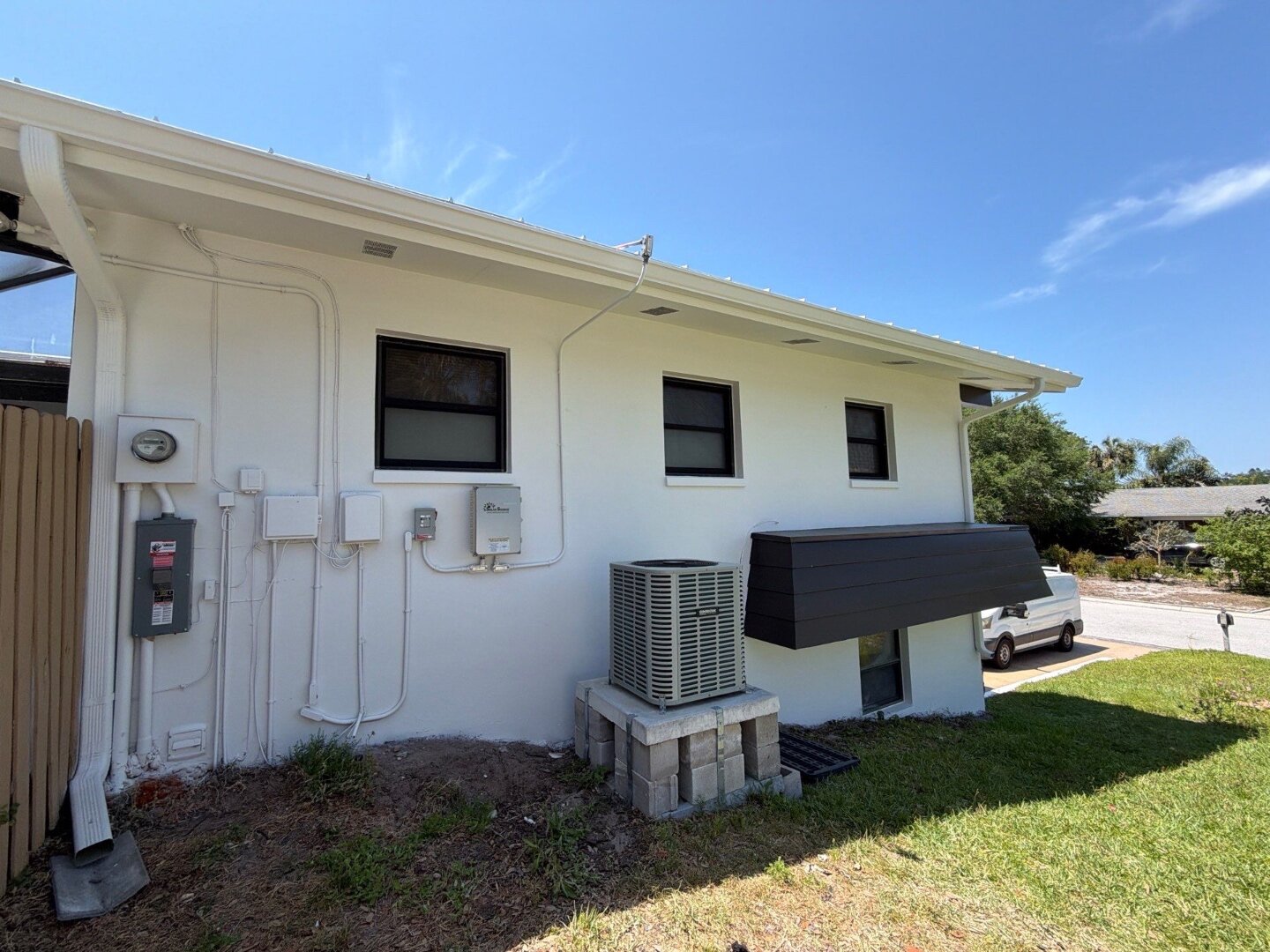 Dunedin home side wall after painting in white Sherwin-Williams Duration with dark AC cover and clean trim