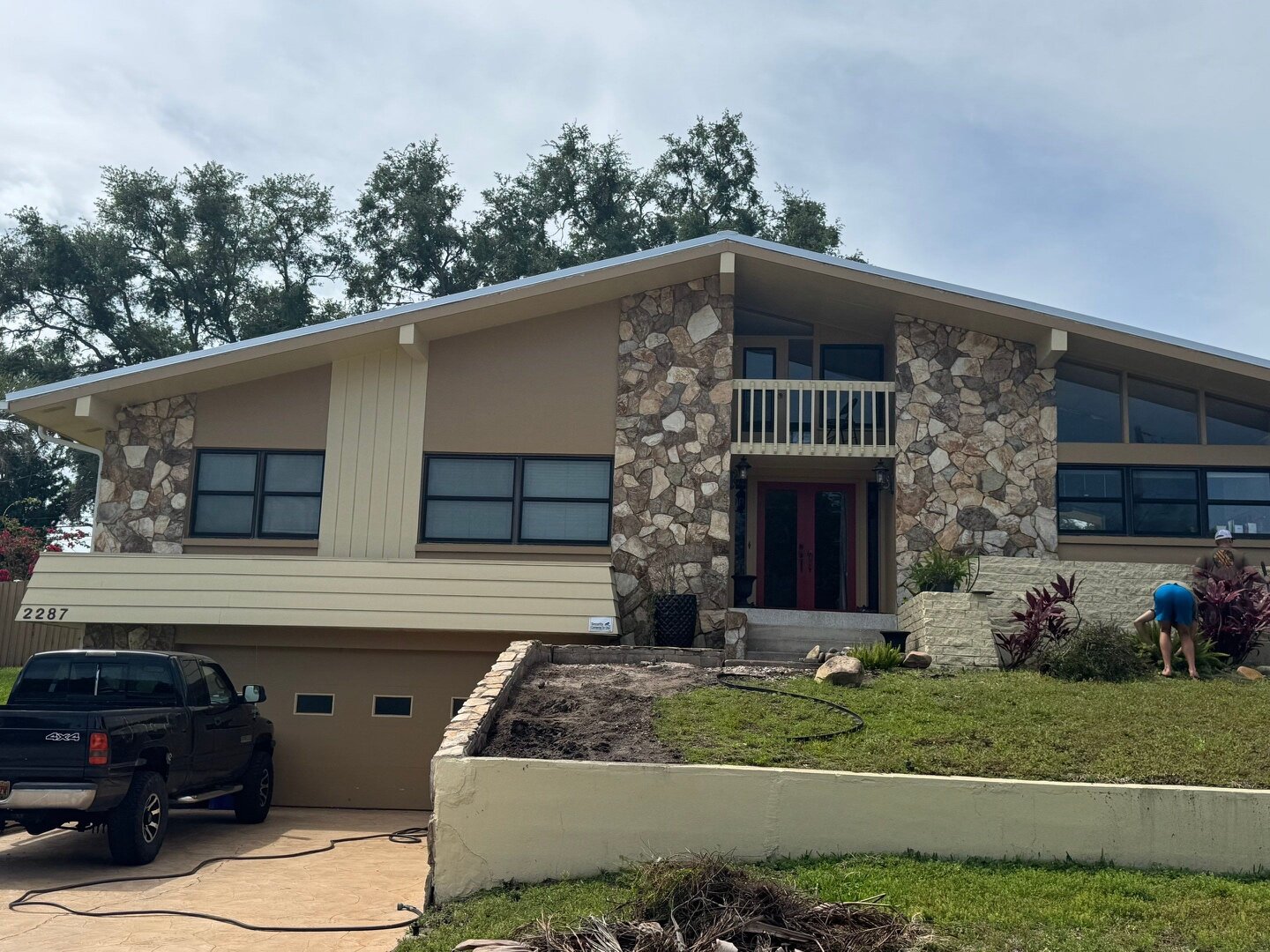 Dunedin Florida mid-century home exterior before painting, with original brown stucco, beige siding, and tan trim